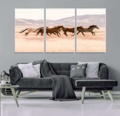 A herd of wild horses galloping through a sunlit desert plain with mountains in the background, perfect for rustic or western-themed wall decor.