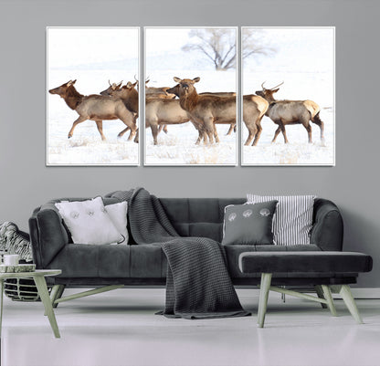 A group of elk standing on snowy terrain with a tree in the background, perfect for rustic or lodge-style winter wall decor.