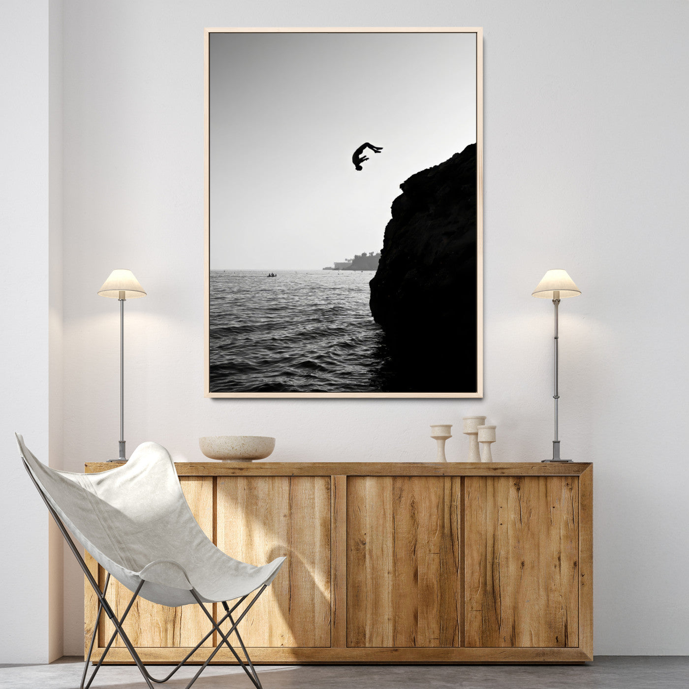 Silhouette of a person mid-air during a cliff jump over the ocean, captured in black and white for minimalist adventure decor.