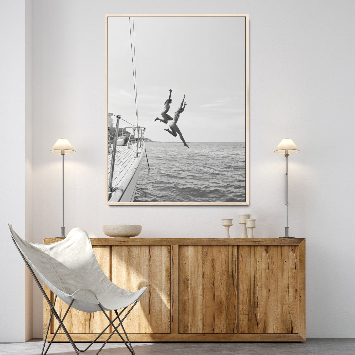 Black and white canvas wall art of two women joyfully jumping off a yacht into the sea, ideal for minimalist coastal or nautical-themed spaces.
