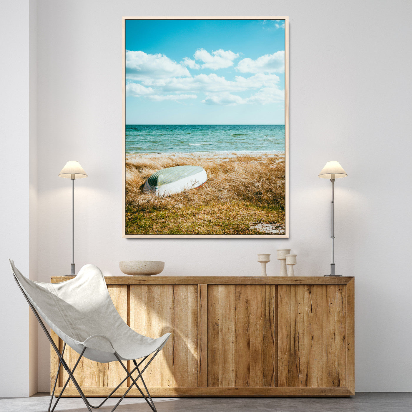A small boat resting on a grassy shore with ocean waves and a bright blue sky, creating a peaceful coastal atmosphere.
