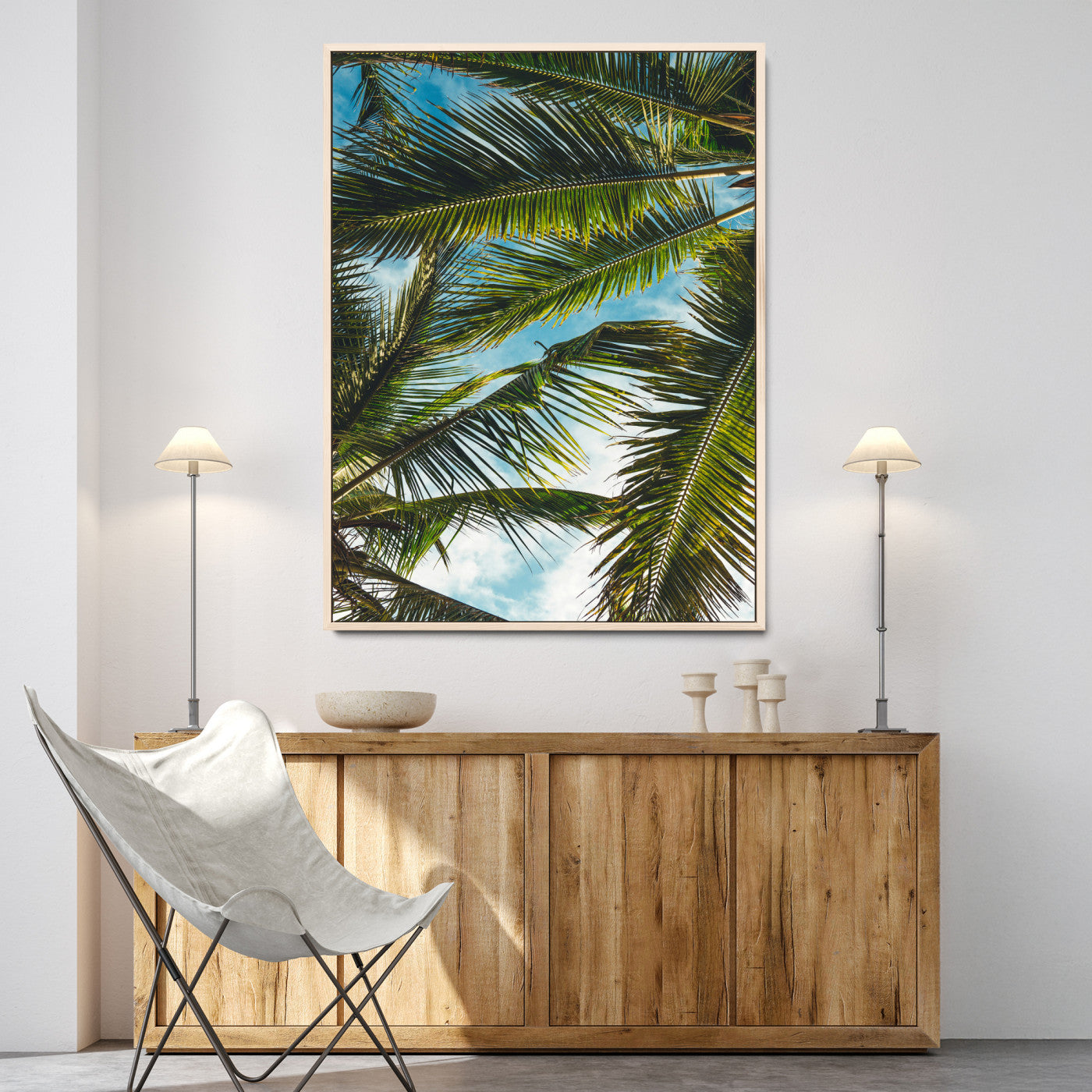Looking up at lush green palm leaves against a bright blue sky, creating a tropical and relaxing coastal aesthetic.