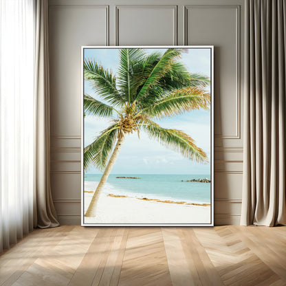 A tall palm tree leaning over a white sandy beach with turquoise ocean waves, creating a peaceful and tropical coastal scene.