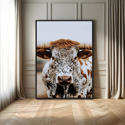 Close-up of a speckled Texas longhorn with wide horns and a bold gaze, perfect for rustic or country-style decor in warm tones.