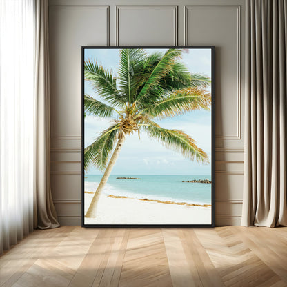 A tall palm tree leaning over a white sandy beach with turquoise ocean waves, creating a peaceful and tropical coastal scene.