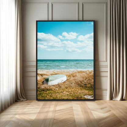 A small boat resting on a grassy shore with ocean waves and a bright blue sky, creating a peaceful coastal atmosphere.
