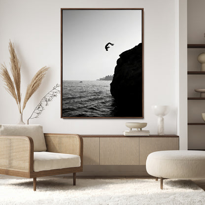 Silhouette of a person mid-air during a cliff jump over the ocean, captured in black and white for minimalist adventure decor.