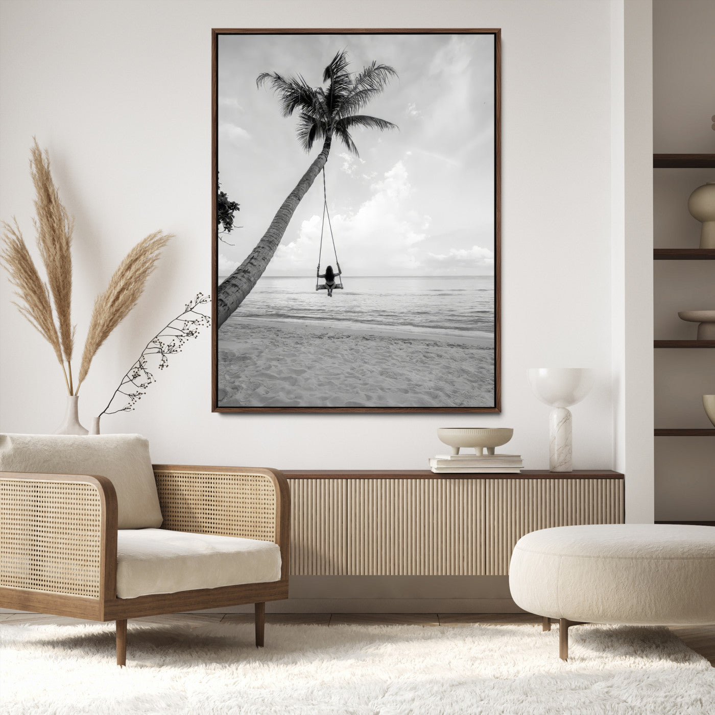 Monochrome photo of a woman swinging from a palm tree on a serene beach, ideal for minimalist or tropical coastal decor.