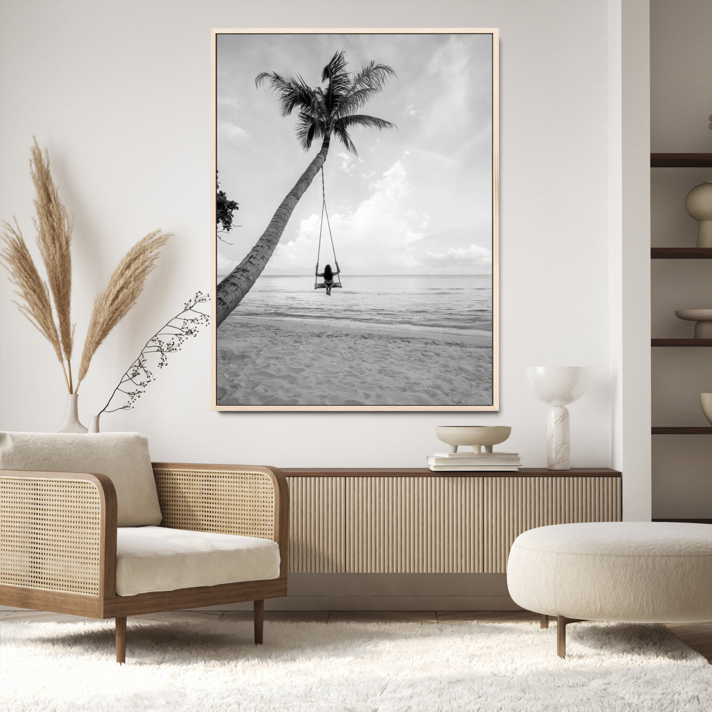 Monochrome photo of a woman swinging from a palm tree on a serene beach, ideal for minimalist or tropical coastal decor.