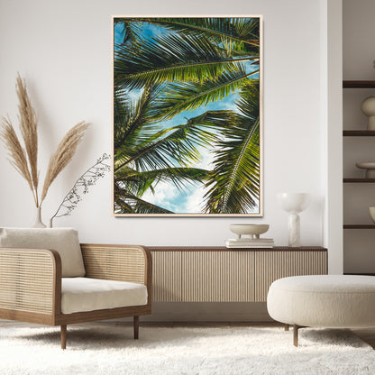 Looking up at lush green palm leaves against a bright blue sky, creating a tropical and relaxing coastal aesthetic.
