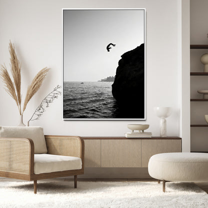 Silhouette of a person mid-air during a cliff jump over the ocean, captured in black and white for minimalist adventure decor.