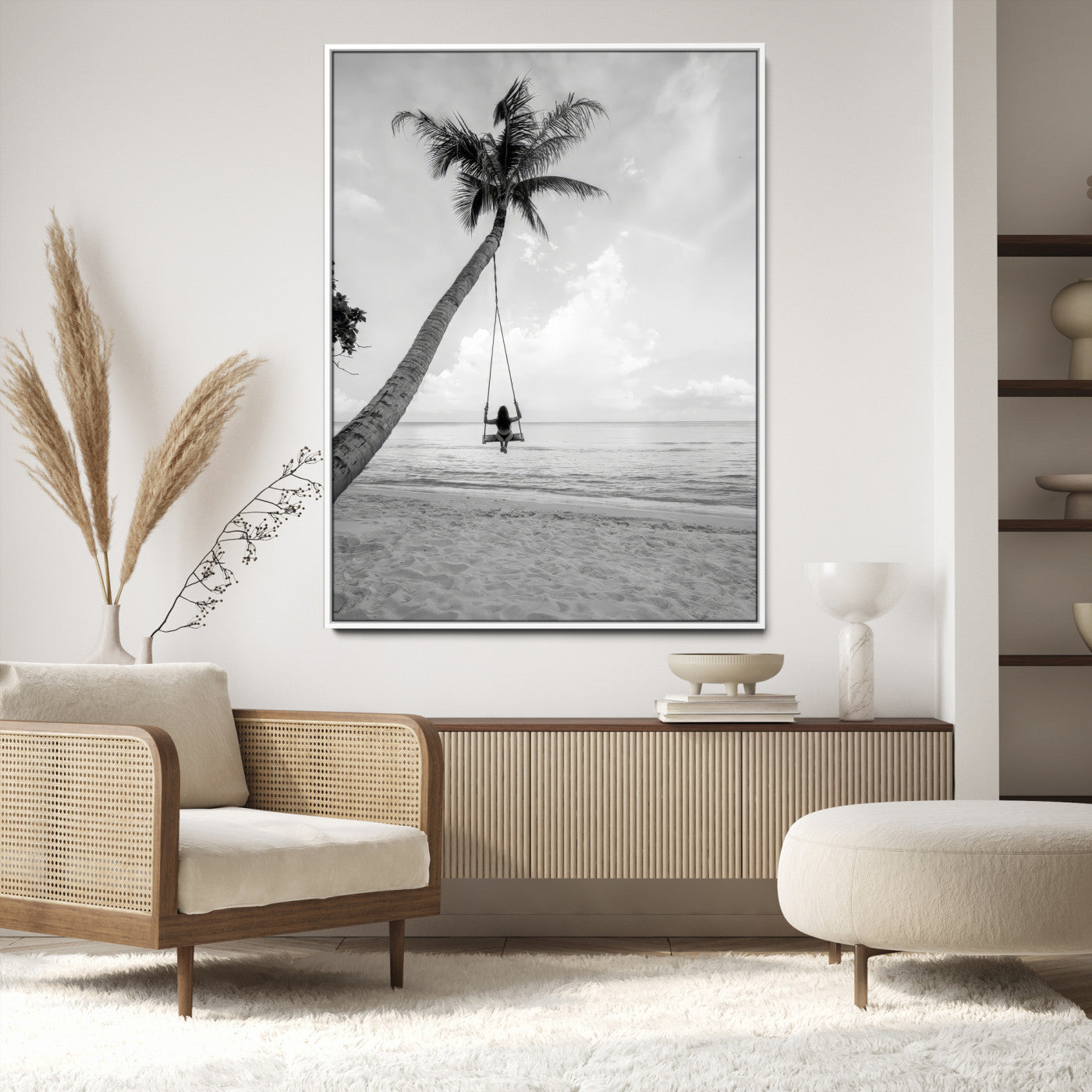 Monochrome photo of a woman swinging from a palm tree on a serene beach, ideal for minimalist or tropical coastal decor.
