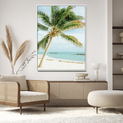 A tall palm tree leaning over a white sandy beach with turquoise ocean waves, creating a peaceful and tropical coastal scene.