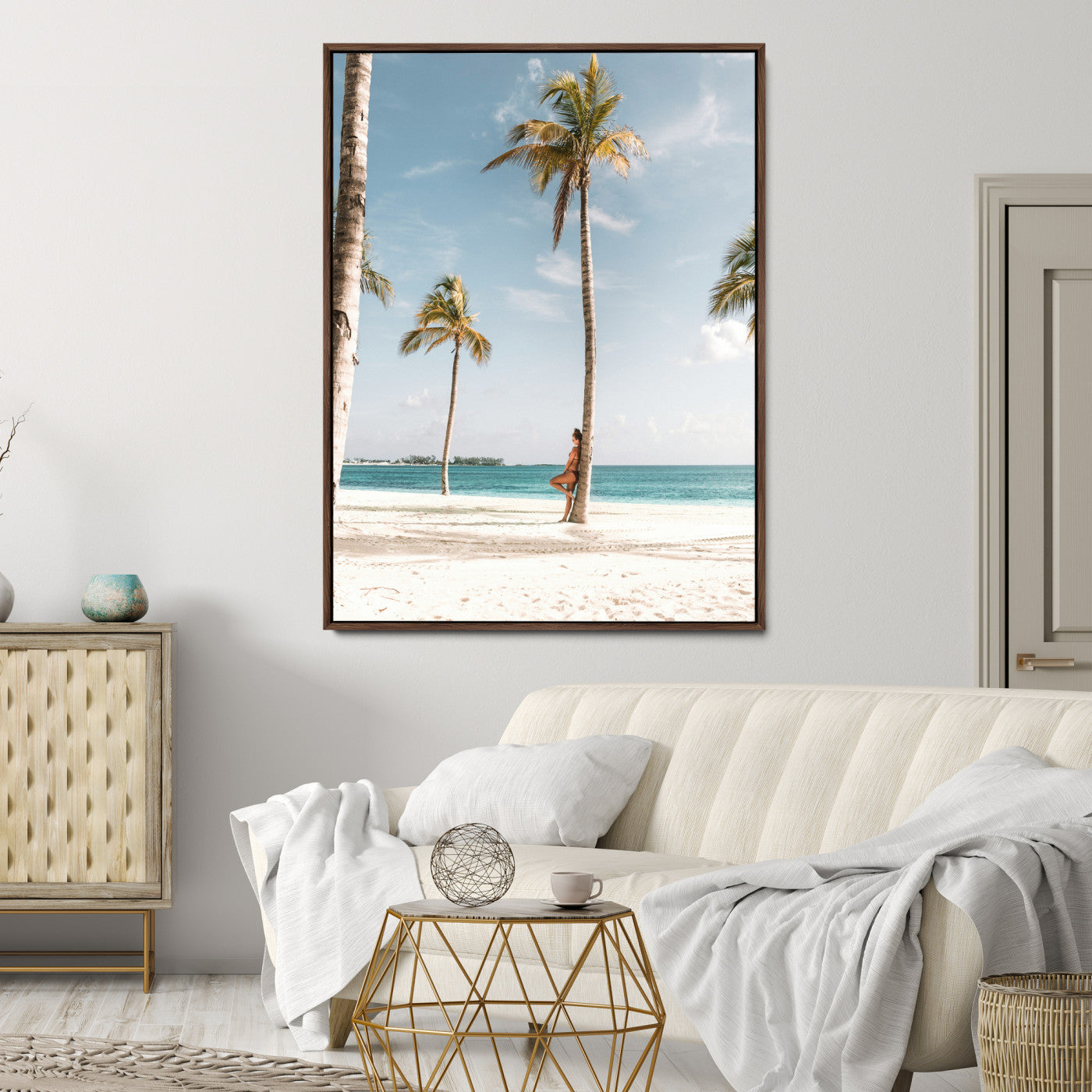 Person leaning on a palm tree at a tropical beach with white sand and turquoise water, perfect for coastal or beach-themed home decor.