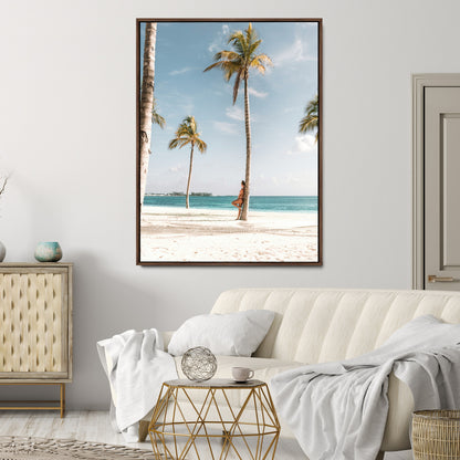 Person leaning on a palm tree at a tropical beach with white sand and turquoise water, perfect for coastal or beach-themed home decor.