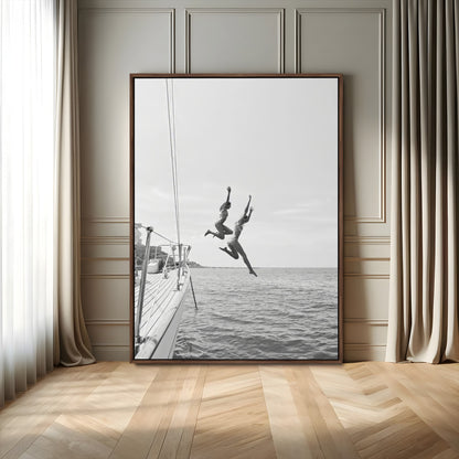 Black and white canvas wall art of two women joyfully jumping off a yacht into the sea, ideal for minimalist coastal or nautical-themed spaces.