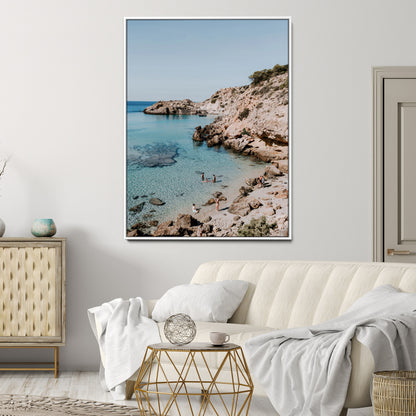 A vibrant coastal photo of a rocky Mediterranean cove with turquoise waters and beachgoers, ideal for boho coastal or summer-inspired interiors.