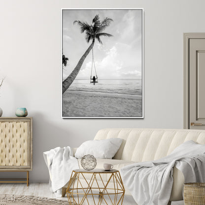 Monochrome photo of a woman swinging from a palm tree on a serene beach, ideal for minimalist or tropical coastal decor.