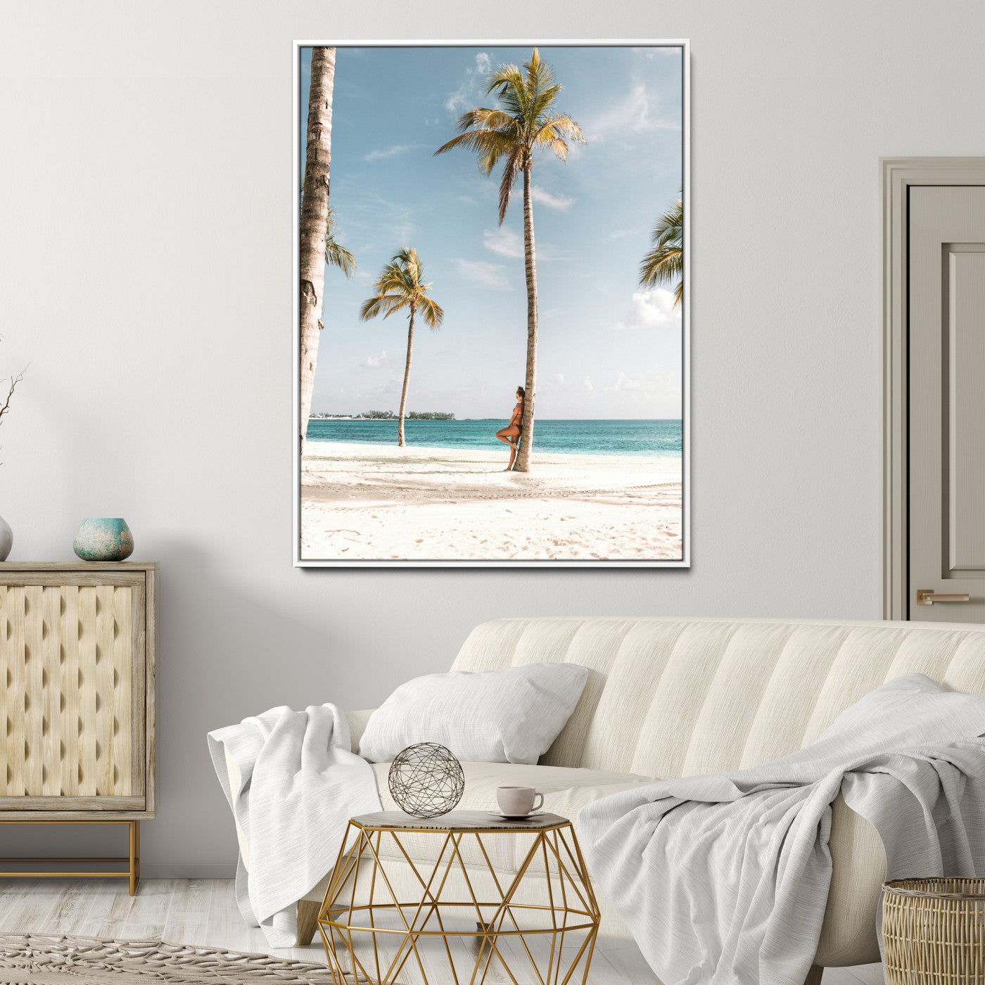Person leaning on a palm tree at a tropical beach with white sand and turquoise water, perfect for coastal or beach-themed home decor.