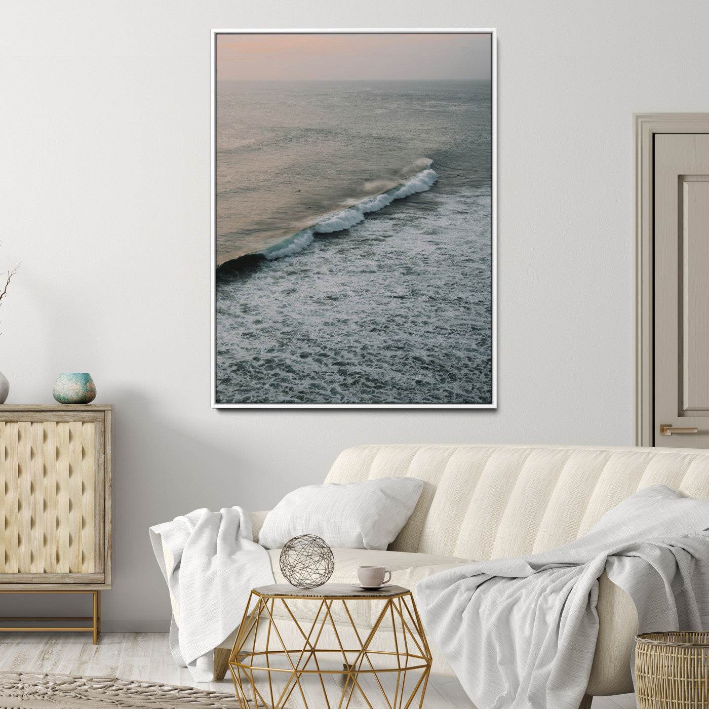 Aerial view of ocean waves rolling towards the shore under a soft sunset sky, creating a peaceful and minimalist coastal scene.
