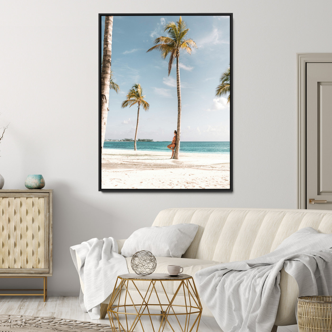 Person leaning on a palm tree at a tropical beach with white sand and turquoise water, perfect for coastal or beach-themed home decor.