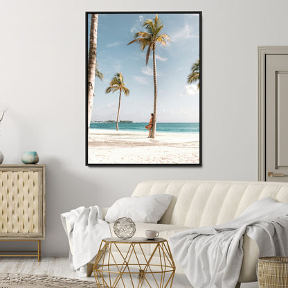Person leaning on a palm tree at a tropical beach with white sand and turquoise water, perfect for coastal or beach-themed home decor.