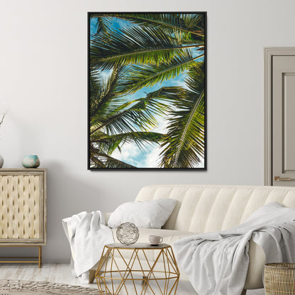 Looking up at lush green palm leaves against a bright blue sky, creating a tropical and relaxing coastal aesthetic.