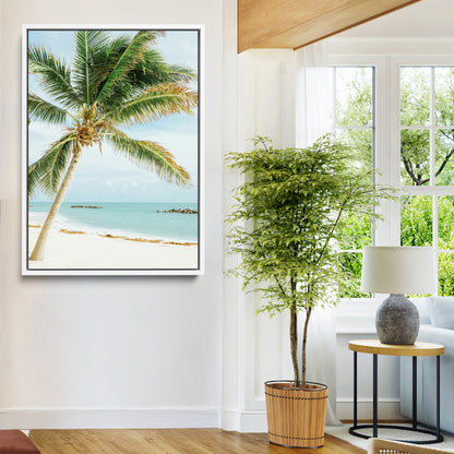 A tall palm tree leaning over a white sandy beach with turquoise ocean waves, creating a peaceful and tropical coastal scene.