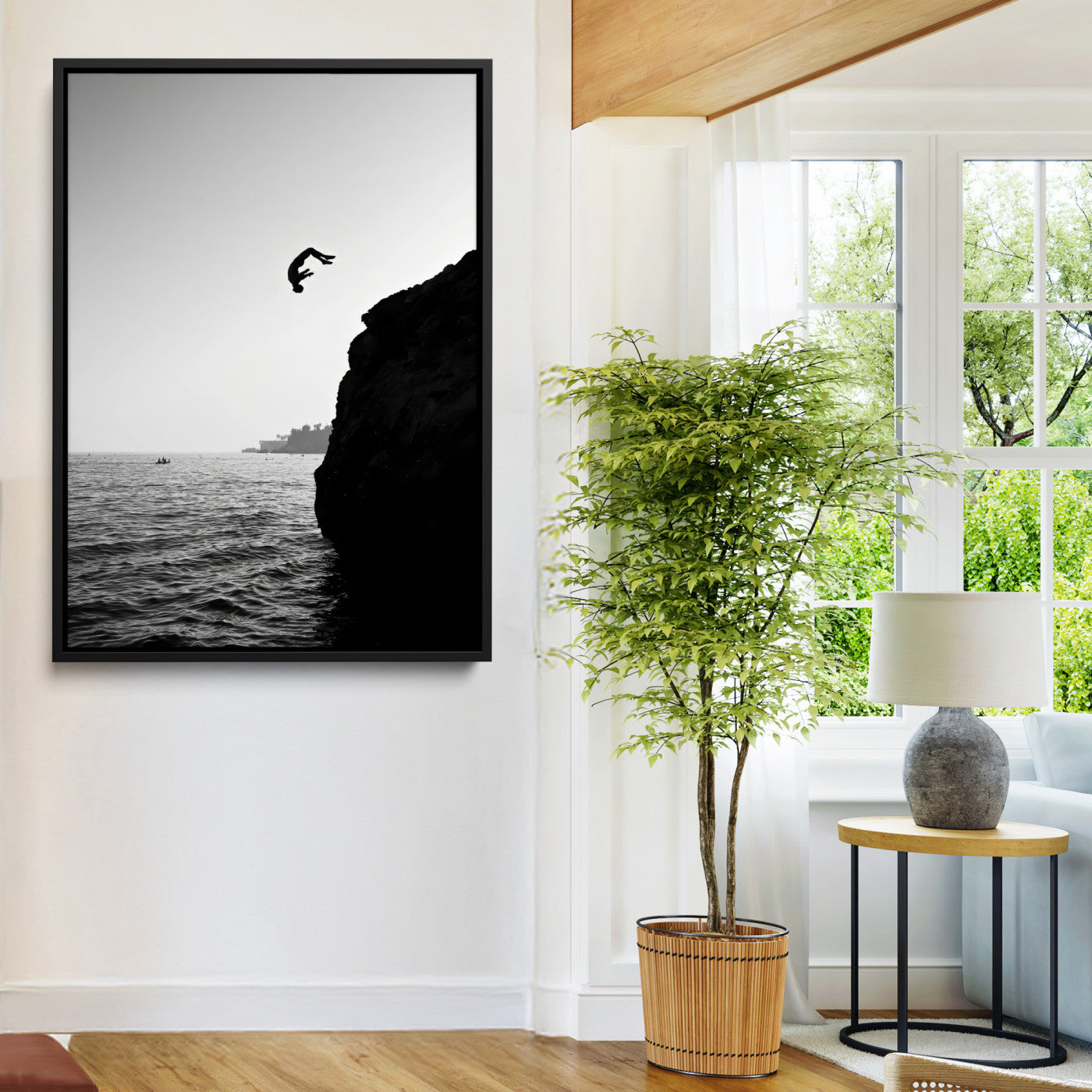 Silhouette of a person mid-air during a cliff jump over the ocean, captured in black and white for minimalist adventure decor.
