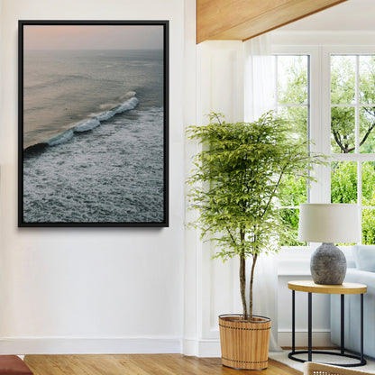 Aerial view of ocean waves rolling towards the shore under a soft sunset sky, creating a peaceful and minimalist coastal scene.