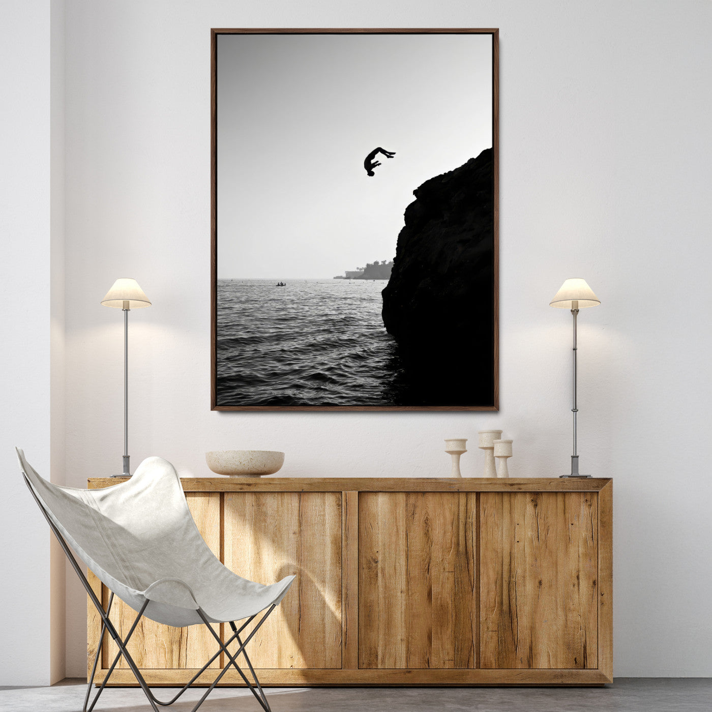 Silhouette of a person mid-air during a cliff jump over the ocean, captured in black and white for minimalist adventure decor.