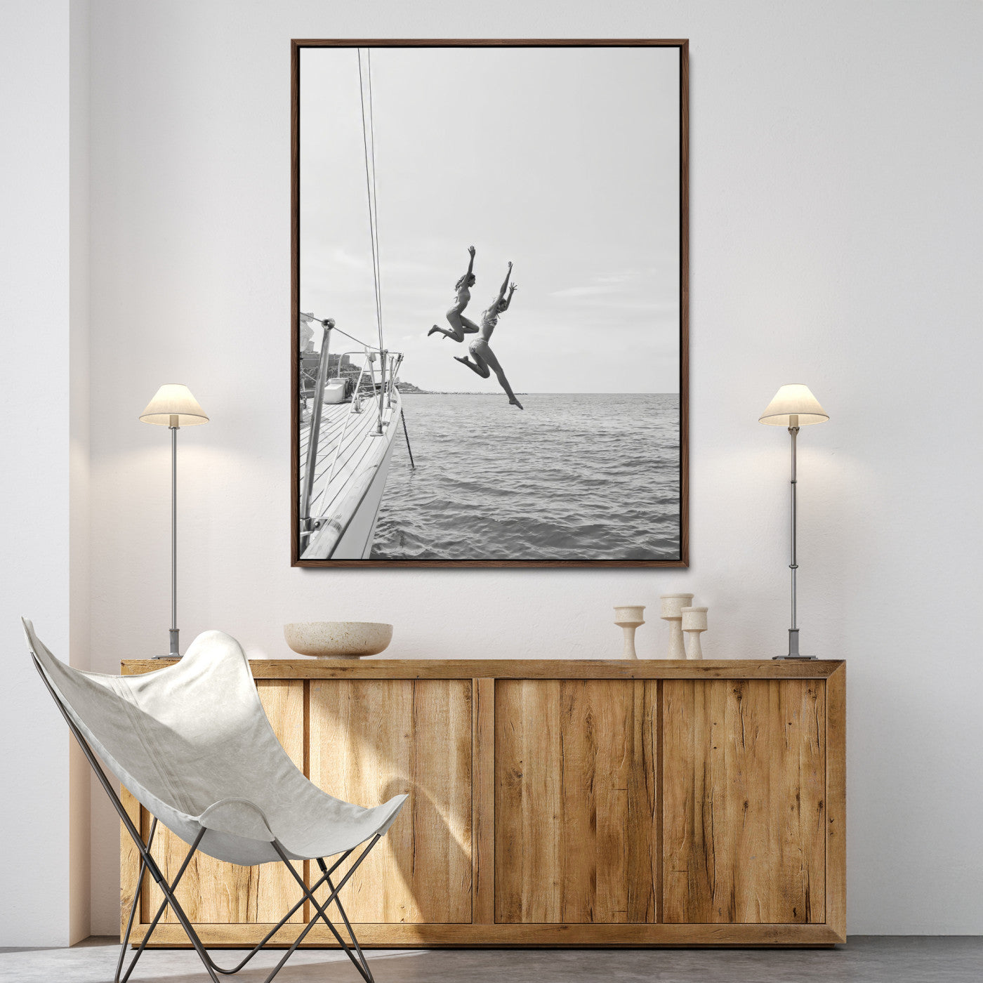 Black and white canvas wall art of two women joyfully jumping off a yacht into the sea, ideal for minimalist coastal or nautical-themed spaces.