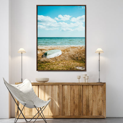 A small boat resting on a grassy shore with ocean waves and a bright blue sky, creating a peaceful coastal atmosphere.