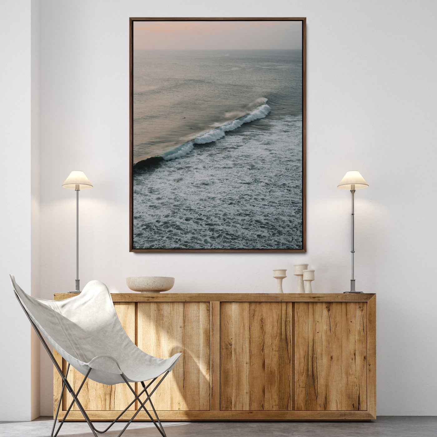 Aerial view of ocean waves rolling towards the shore under a soft sunset sky, creating a peaceful and minimalist coastal scene.