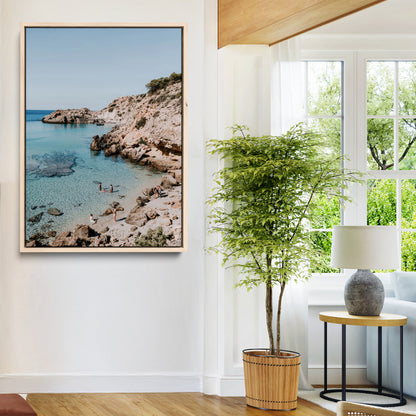 A vibrant coastal photo of a rocky Mediterranean cove with turquoise waters and beachgoers, ideal for boho coastal or summer-inspired interiors.