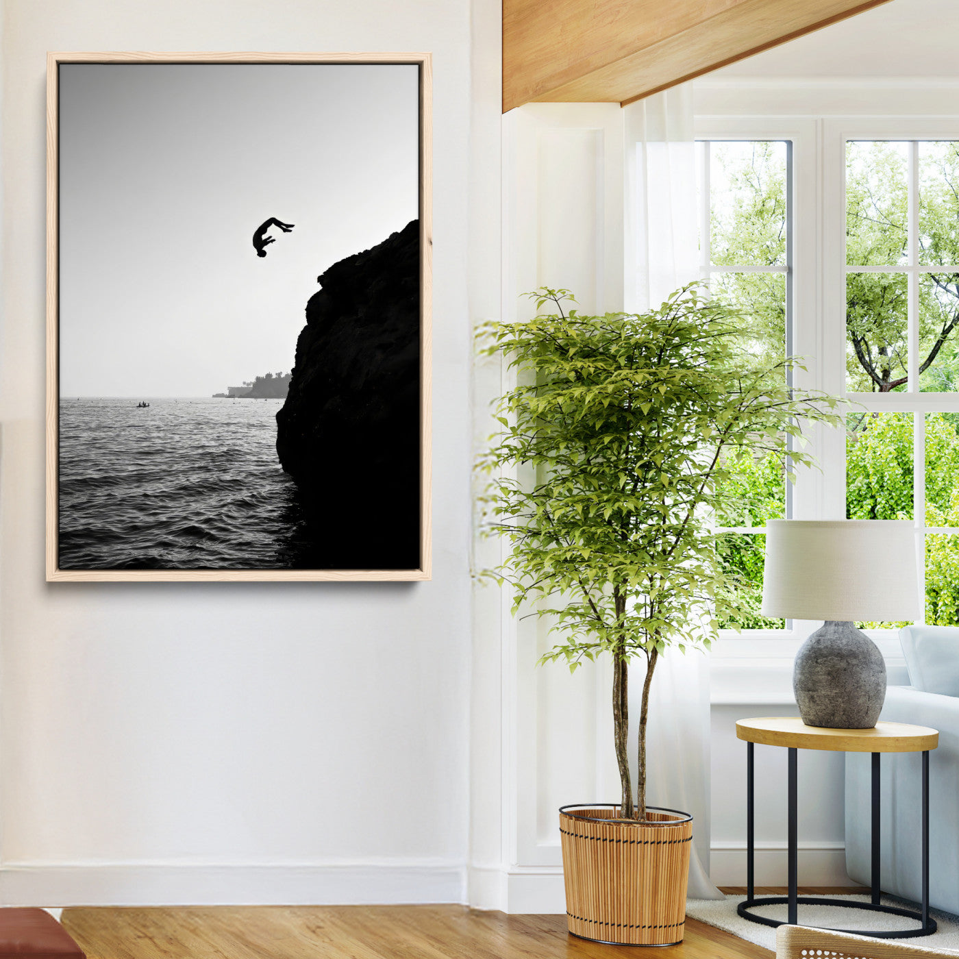 Silhouette of a person mid-air during a cliff jump over the ocean, captured in black and white for minimalist adventure decor.