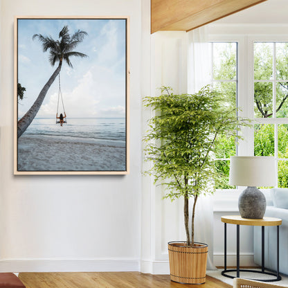 Wall art of a girl on a swing hanging from a palm tree over calm ocean waters, perfect for tropical or minimalist coastal decor.