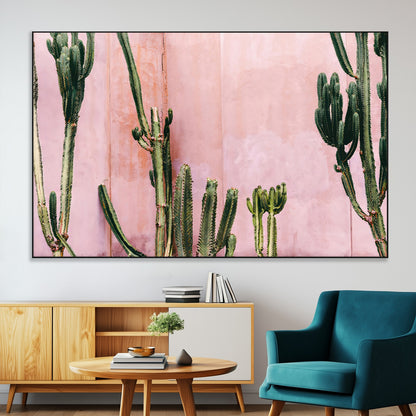 Framed canvas of tall green cacti against a soft pink wall, ideal for modern desert or colorful southwest-inspired home decor.