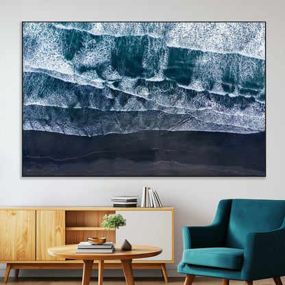 Canvas of aerial ocean waves crashing onto a black sand beach in moody tones, ideal for modern coastal or minimalist home decor.