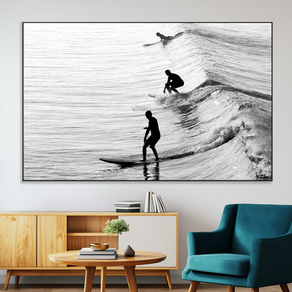 Black and white photo of surfers riding waves in a moody, high-contrast scene, ideal for modern coastal or surf-inspired home decor.