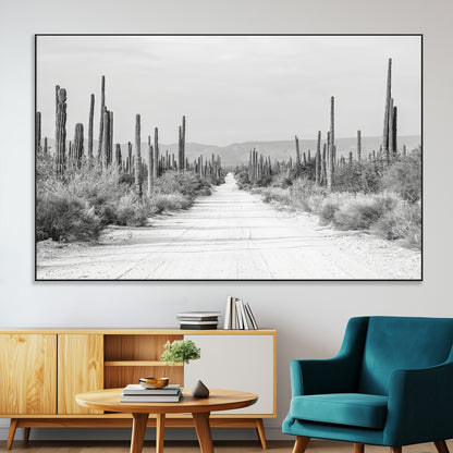 A black and white desert road stretching through a cactus-filled landscape, creating a rugged and timeless southwestern aesthetic with a sense of adventure.