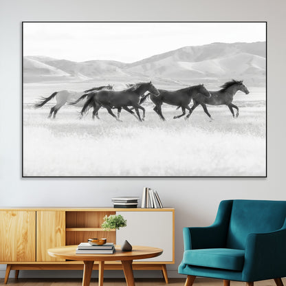 A black and white image of wild horses running freely across an open grassland, capturing the power and beauty of untamed nature in a rustic western setting.