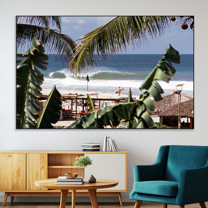 Canvas wall art of a tropical surf scene framed by palm trees, with a surfer on the shore and waves rolling in, ideal for beach-themed decor.