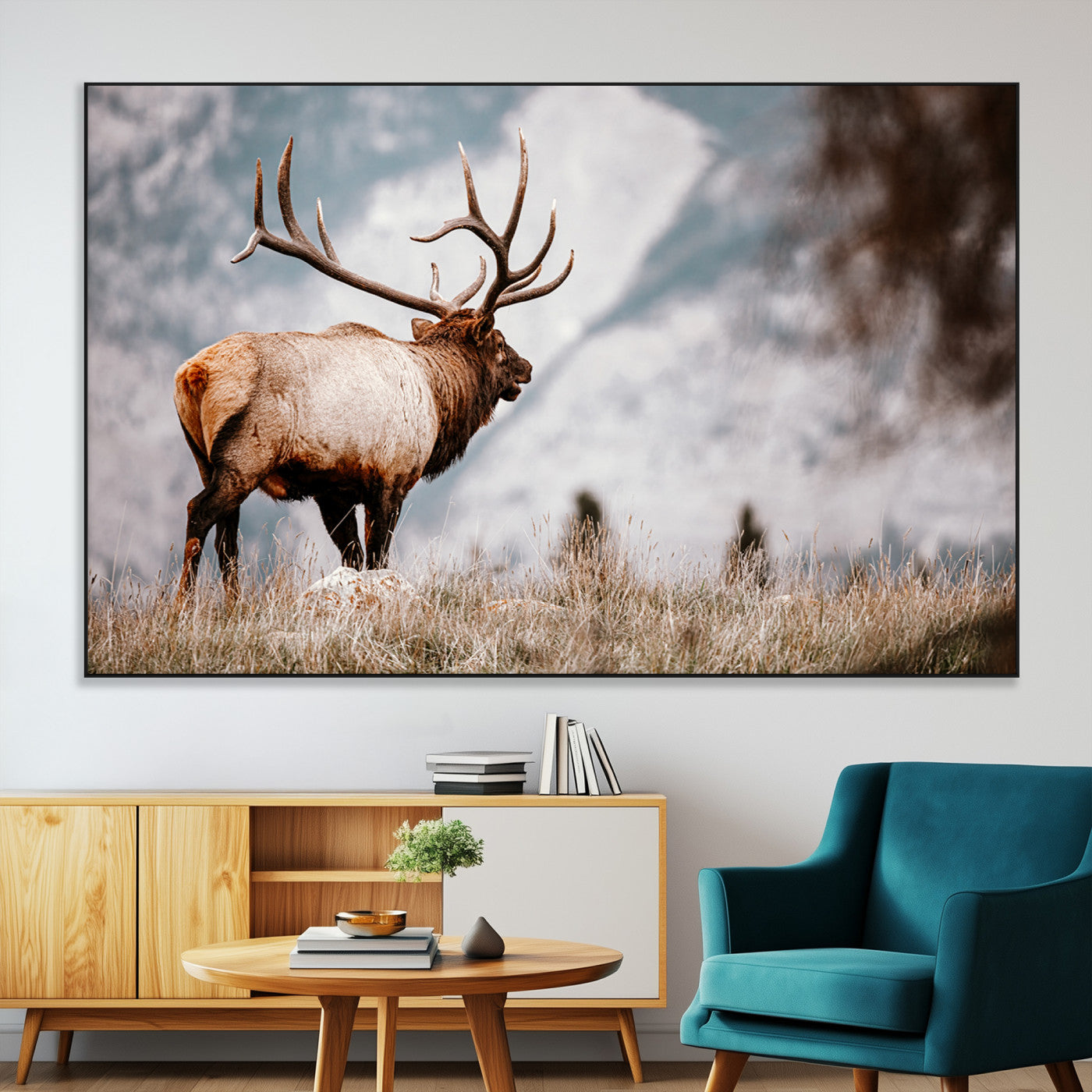 Majestic elk with large antlers standing in grass with snowy mountains in background, perfect for rustic cabin or lodge style decor.