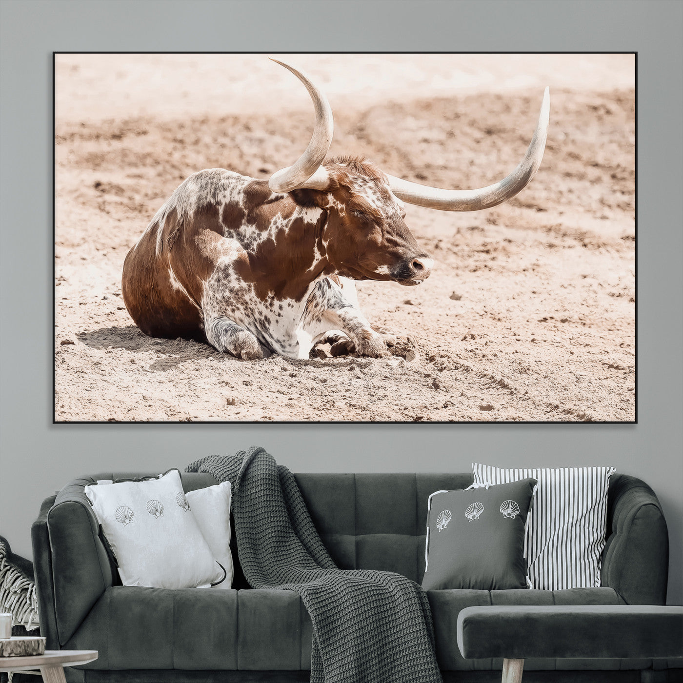 Texas Longhorn bull resting on dusty ground with warm tones, ideal for rustic western or farmhouse-themed wall decor.