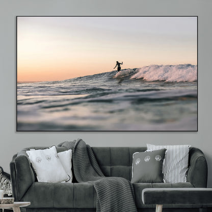Framed canvas of a female surfer balancing on a wave at sunset, perfect for serene surf or ocean-inspired coastal decor.