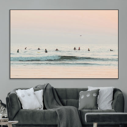 Dreamy photo of surfers waiting on soft pastel waves under a pink sunset sky, ideal for soft coastal minimalist or serene ocean-themed home decor.