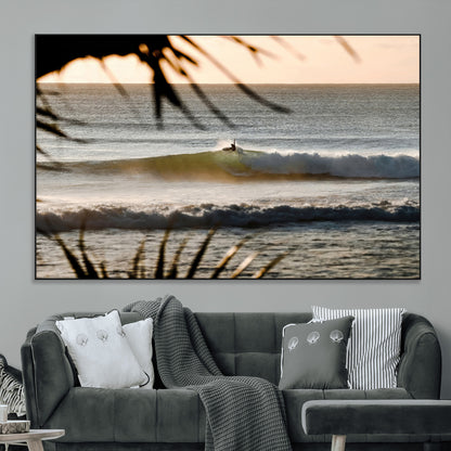 Photo of a surfer riding a golden hour wave at sunset, with tropical tones and dreamy light, perfect for tropical boho or coastal home decor.