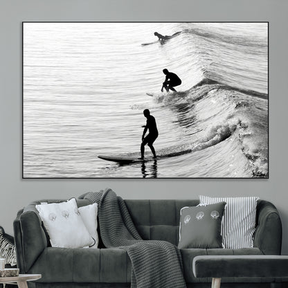 Black and white photo of surfers riding waves in a moody, high-contrast scene, ideal for modern coastal or surf-inspired home decor.