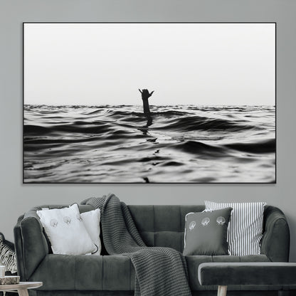 Black and white ocean with a hand making a surfer sign among dark waves, creating a dramatic and minimalist seascape with bold contrast.